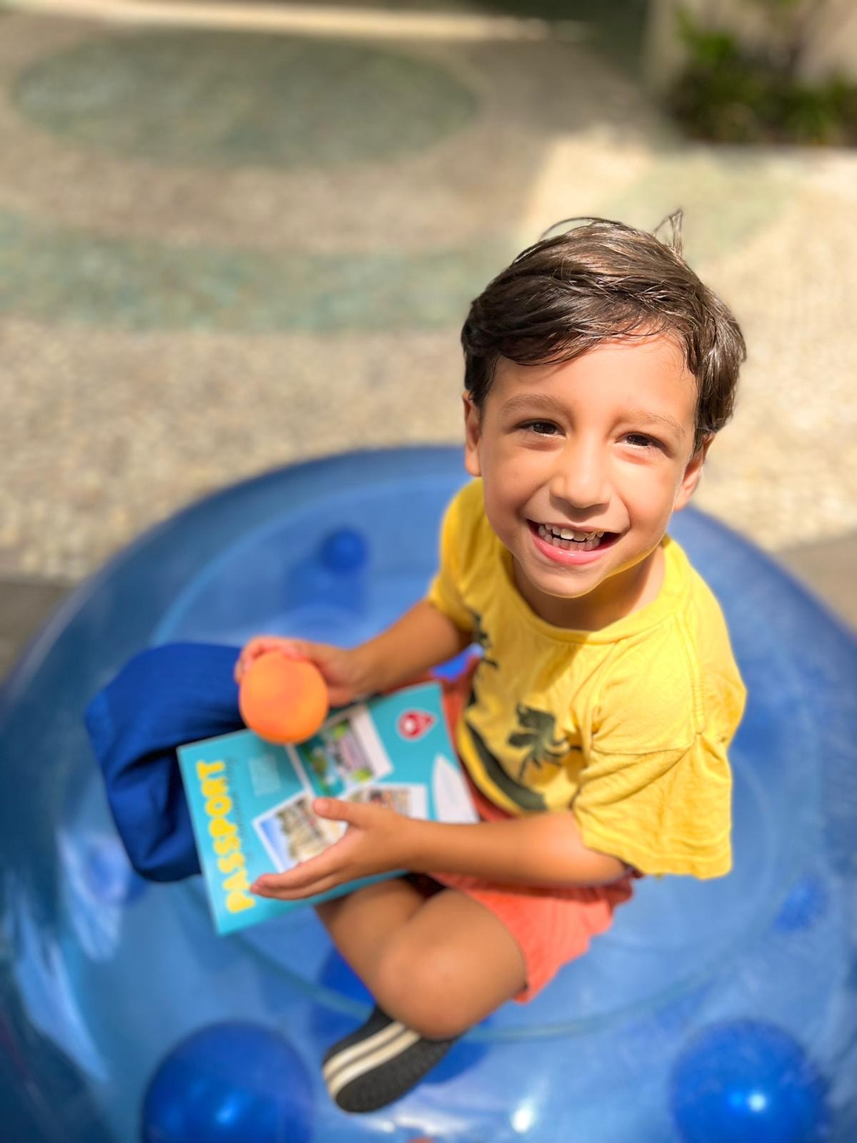 Boy in yellow shirt holds book.