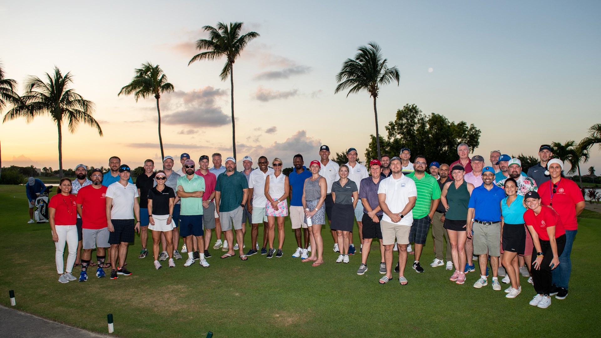 group of golfers pose at sunset