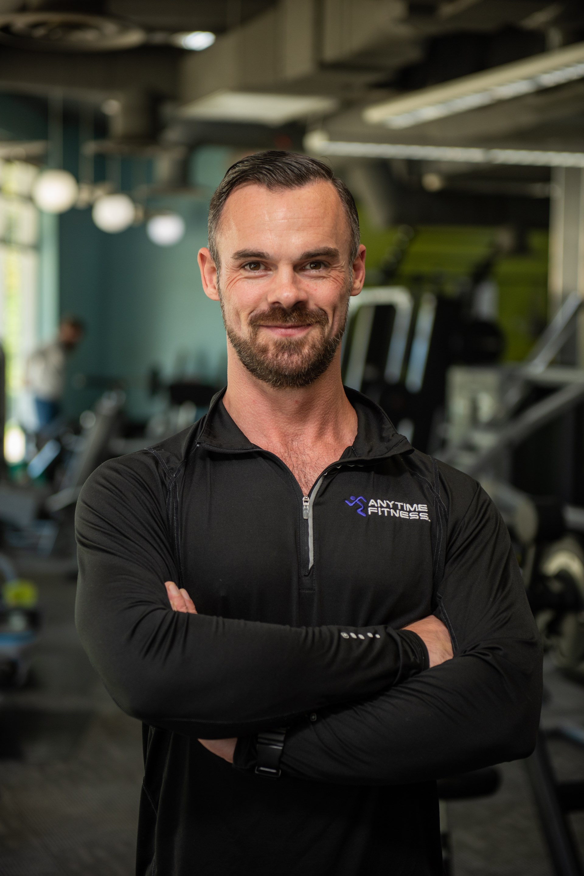 Man poses with arms crossed in gym