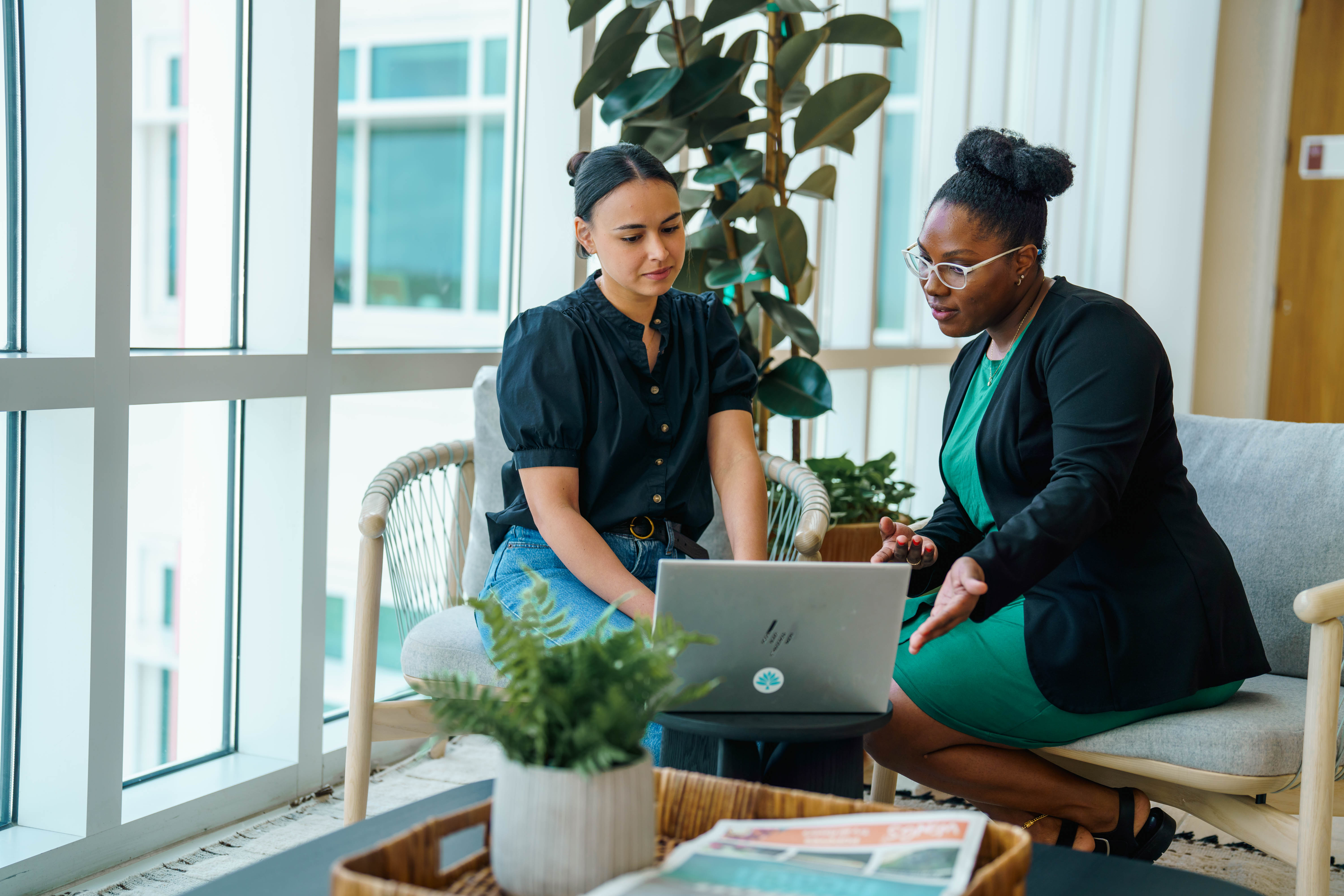 Two women sitting and working on laptop