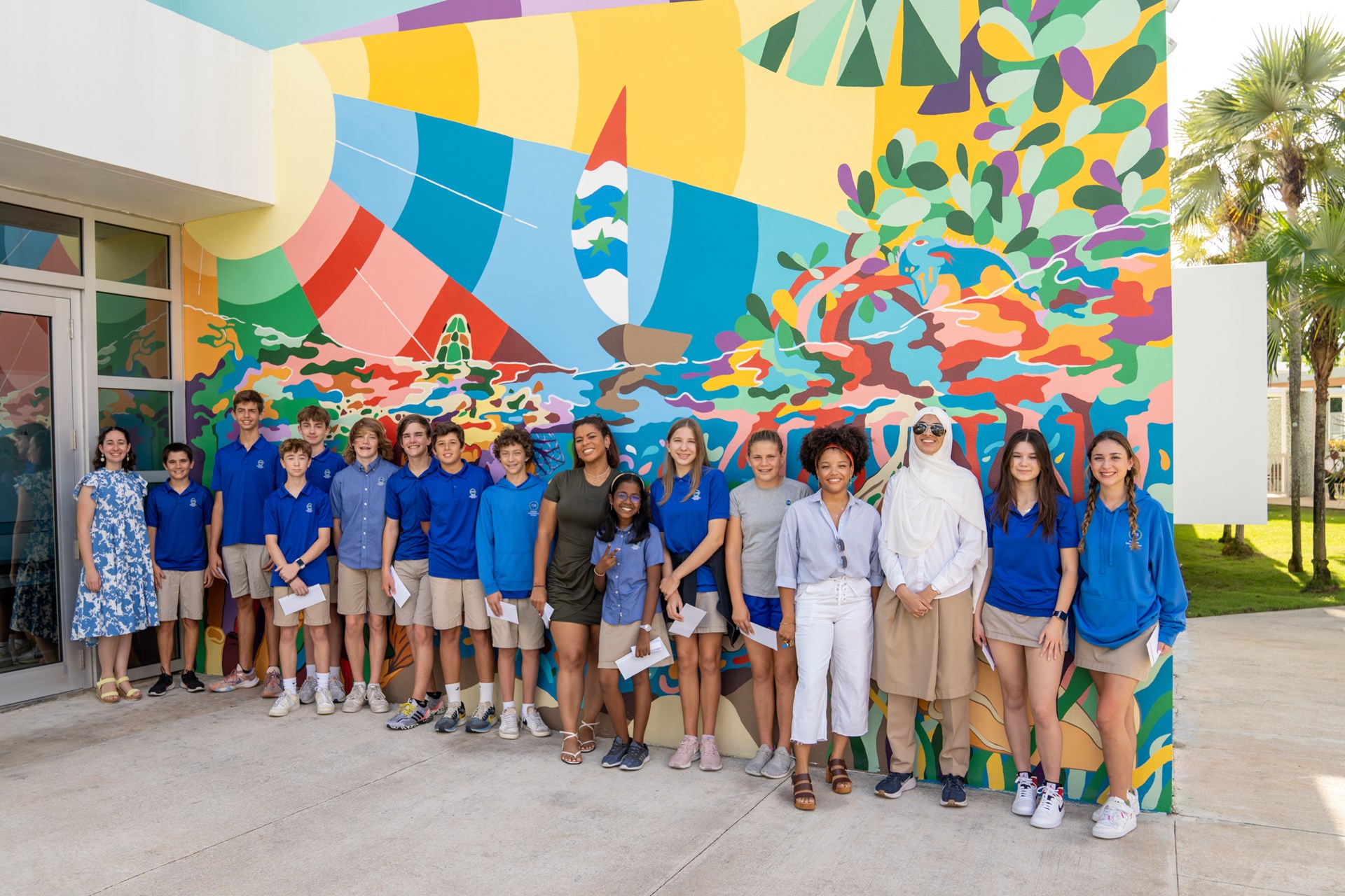 Students and visual designers standing in front of abstract mural.