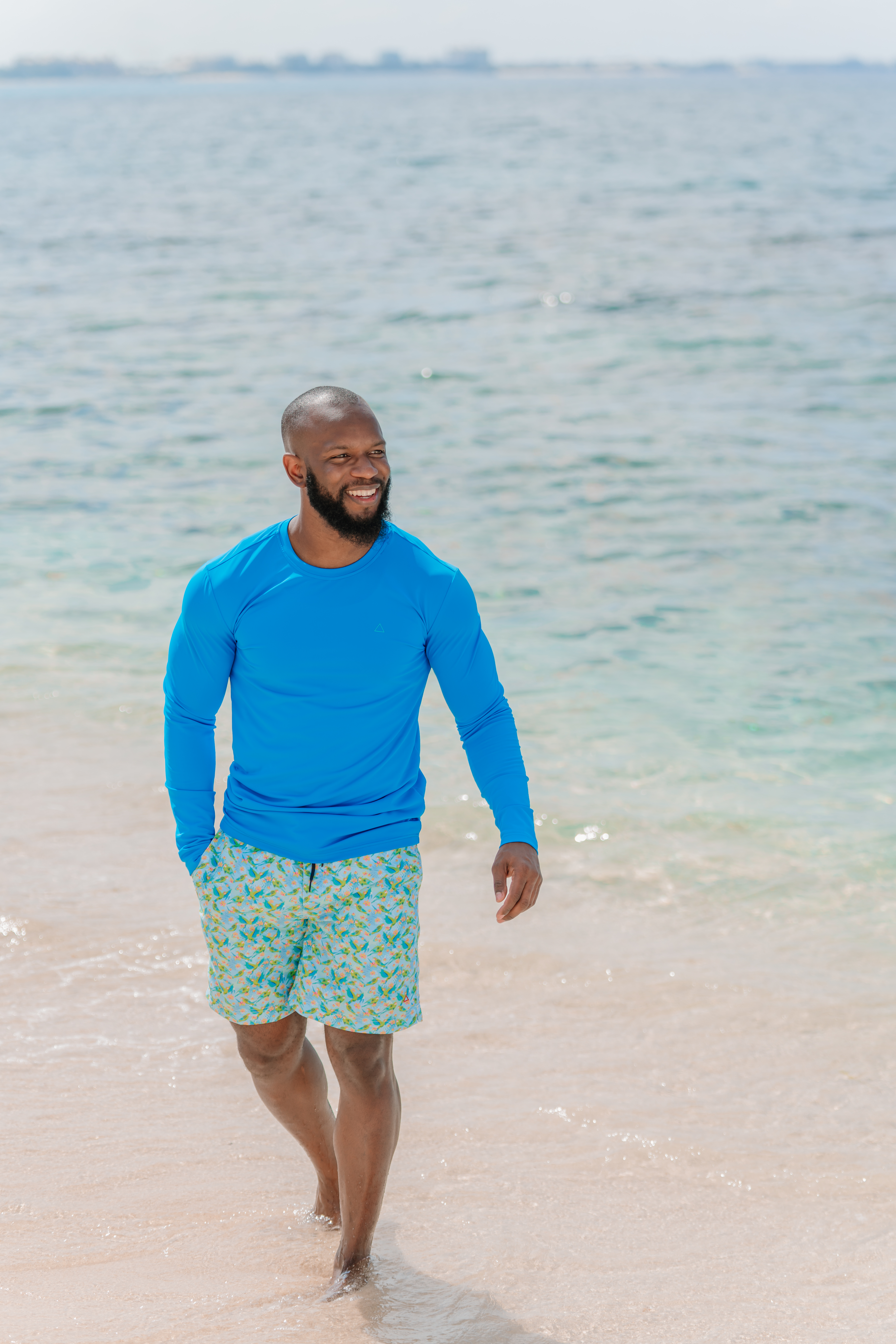 Black man walking on the beach in blue shirt