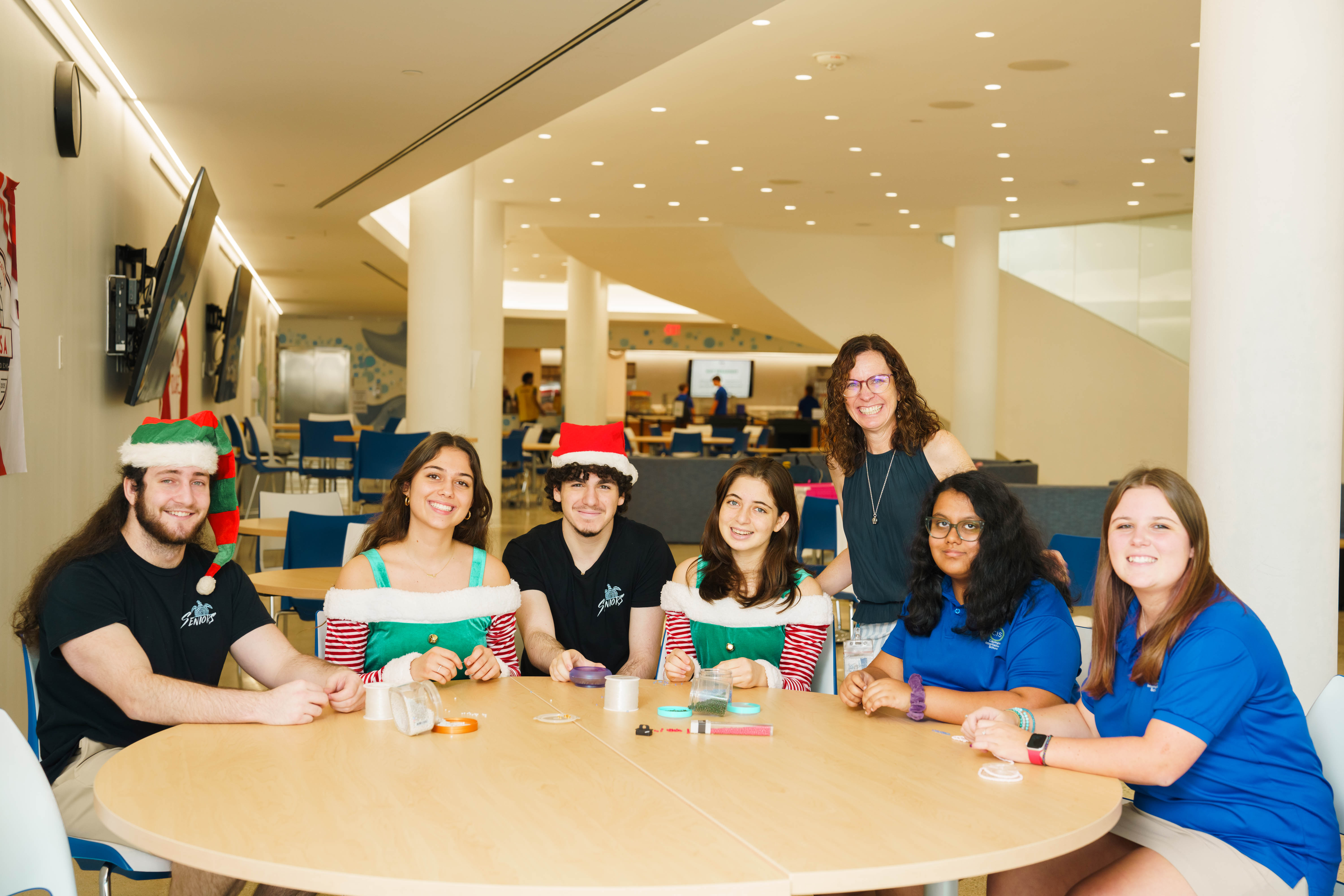 CIS students sat around desk making holiday bracelets