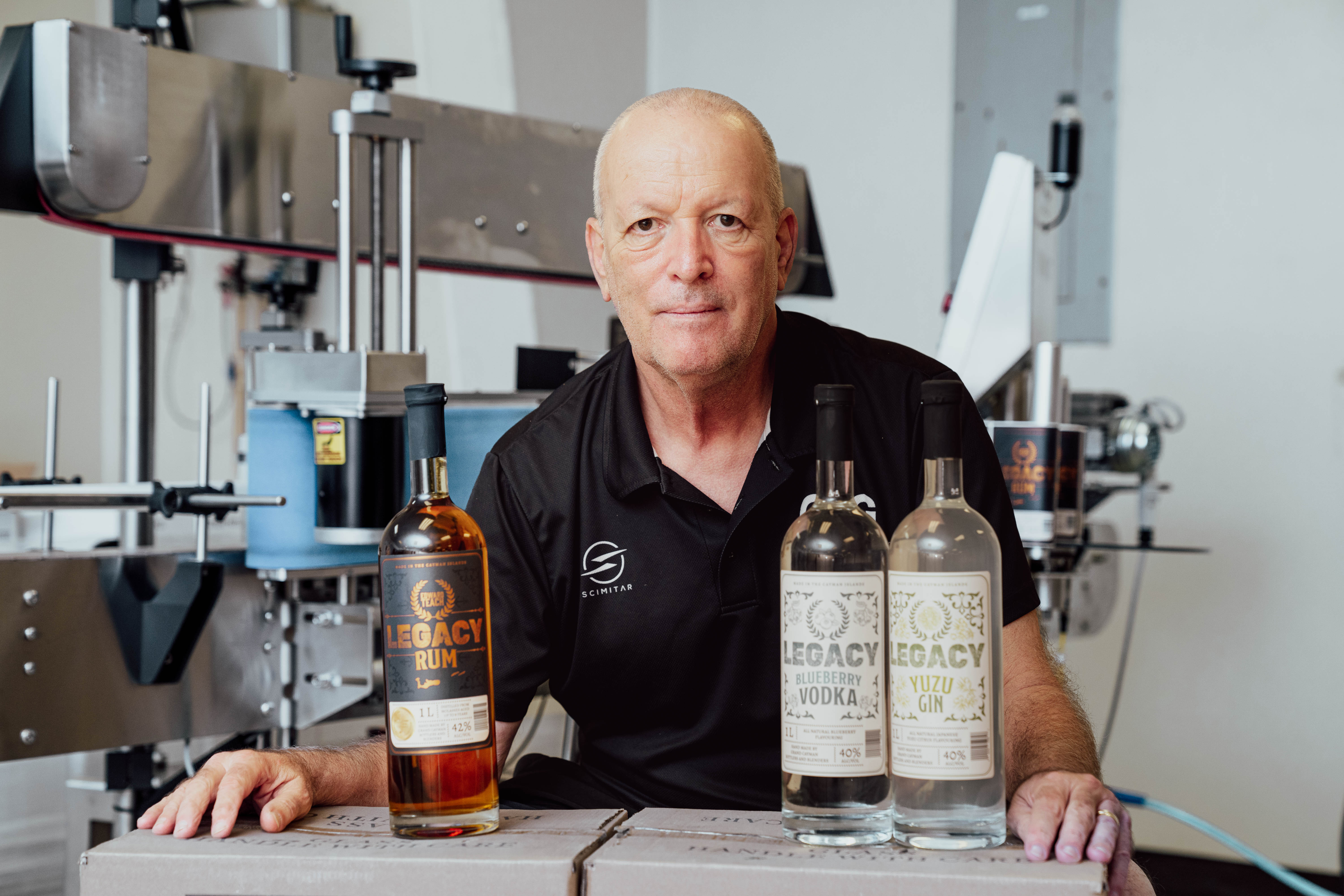 Man poses for camera with bottles of local spirits